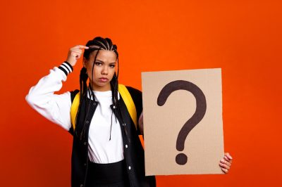 young woman holding cardboard sign with a question mark
