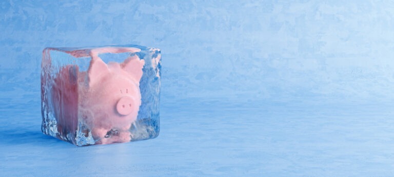 Pink piggy bank frozen in ice cube, frozen account concept, cold blue ice background