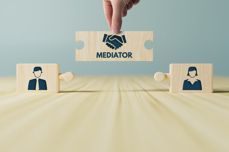 Two wooden blocks with someone holding a puzzle piece with "mediation" in between them