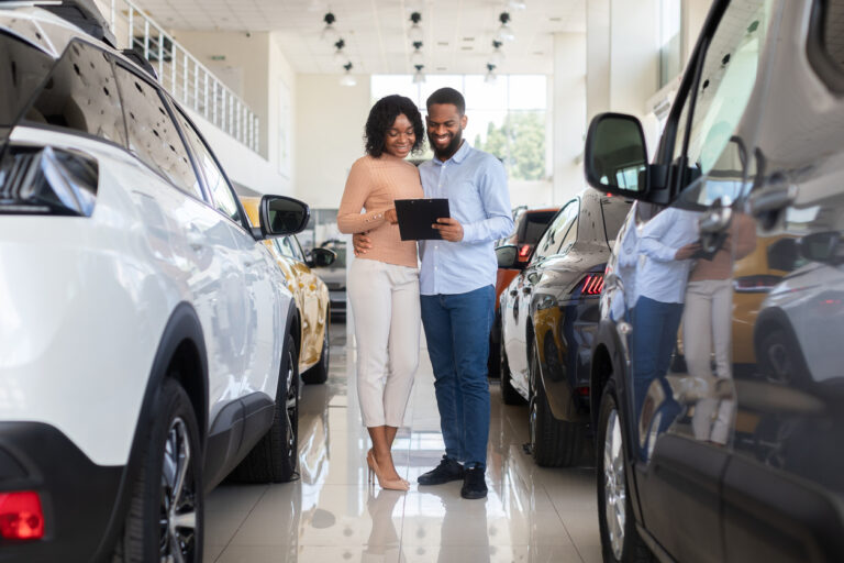 Young couple buying new car on showroom floor