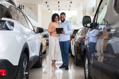 Young couple buying new car on showroom floor
