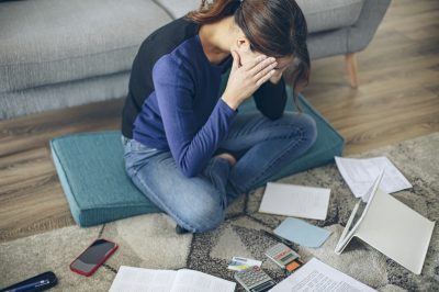 Woman sitting on living room floor looking at credit card debt