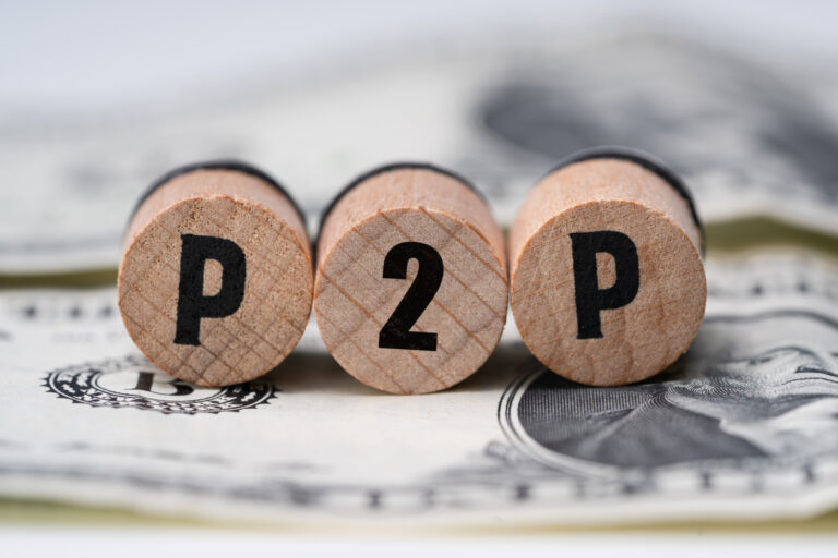P2P on wooden blocks on American cash. Peer to peer loan concept.