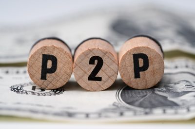 P2P on wooden blocks on American cash. Peer to peer loan concept.