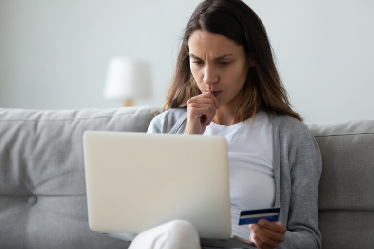 Woman on couch confused holding credit card