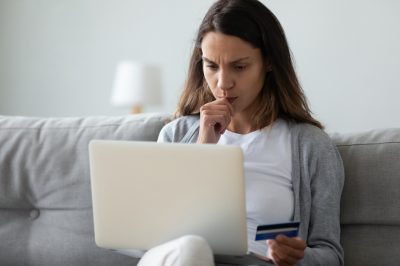 Woman on couch confused holding credit card