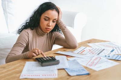 Stressed young woman looking at debt collection notices