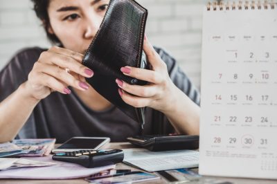 Woman looking in wallet for money next to calendar