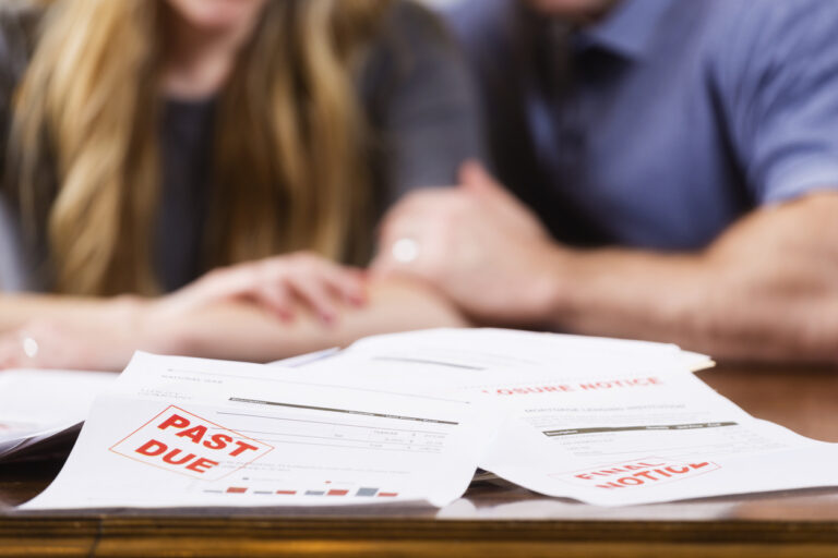 A man and woman overwhelmed with past-due bills and debt.