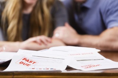 A man and woman overwhelmed with past-due bills and debt.
