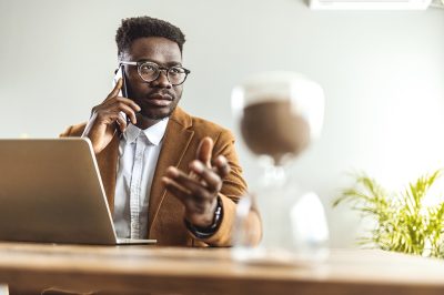 a man sits at a desk with a laptop, talking on his phone