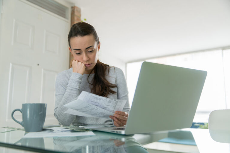 Woman paying her utility bills online and looking worried