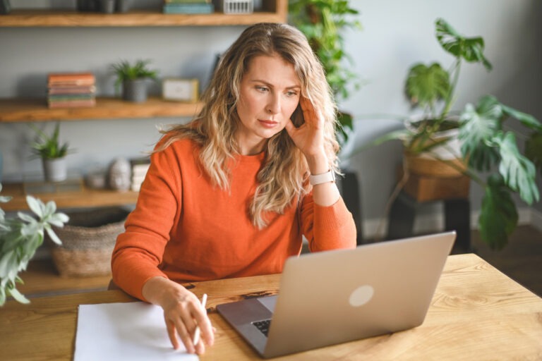 Woman at table on laptop contemplating personal loan for debt consolidation
