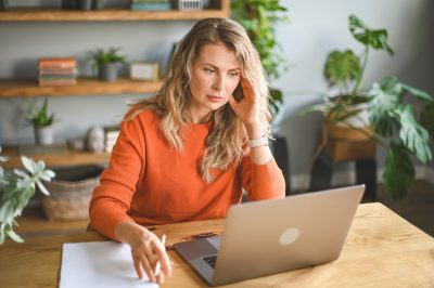 Woman at table on laptop contemplating personal loan for debt consolidation