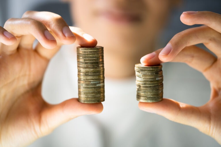 Man holding two stacks of coins, comparing financial options