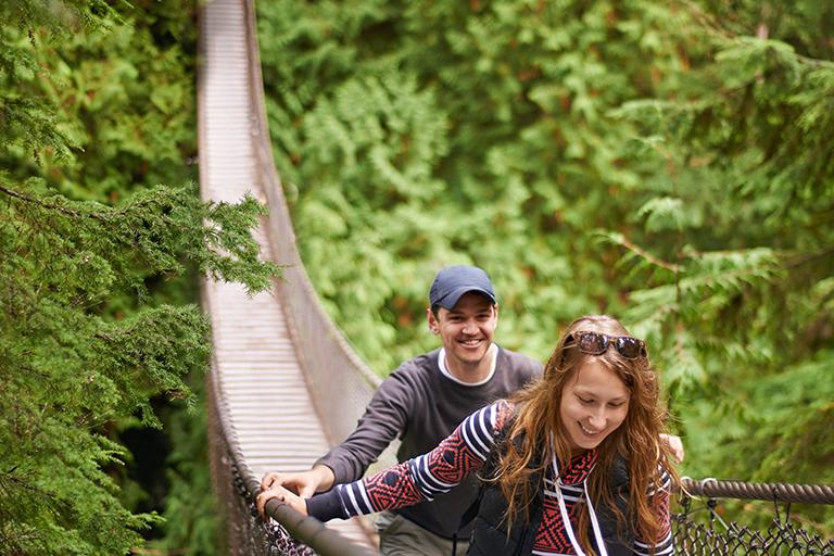 Two friends walking across a bridge in a wooded area
