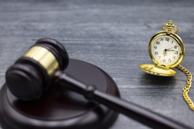 Gavel and Block with antique pocket watch on desk.