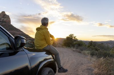 Man sitting on hood of car watching sunset - wondering about future