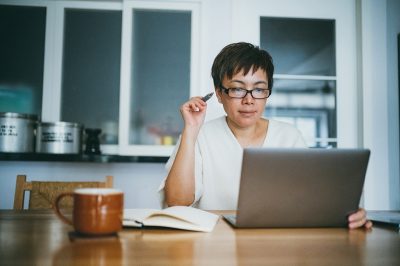 Asian senior woman working on her home finance with laptop at home