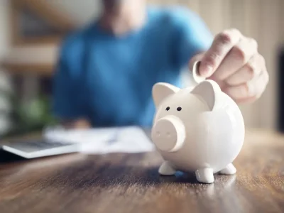 a person puts a coin into a piggy bank